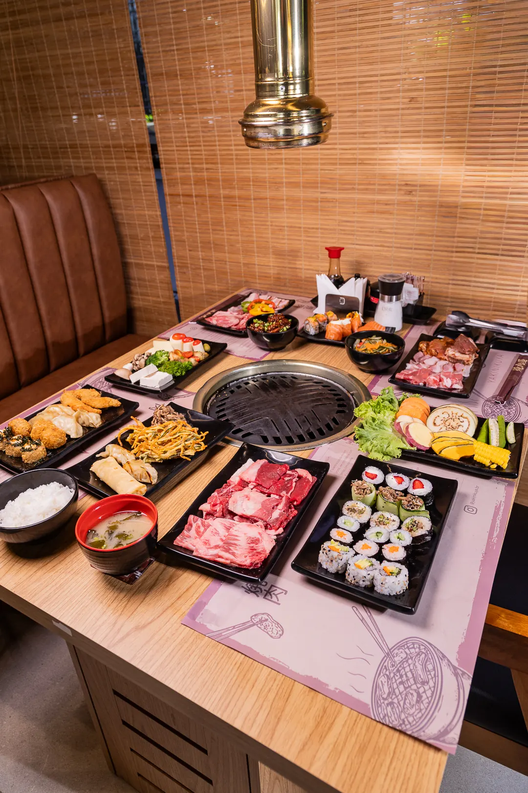 Mesa de rodízio posta com carnes, sushi e acompanhamentos ao redor da grelha