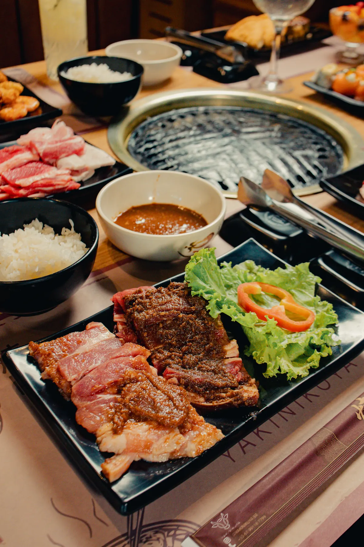 Mesa com grelha, cortes de carne e acompanhamentos